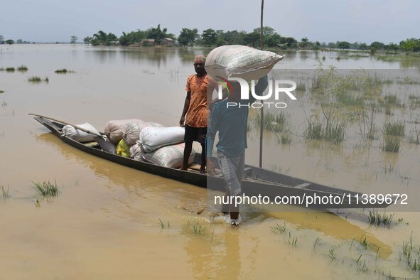 Villagers are shifting liquefied sacks of rice to a safer place in Nagaon District of Assam, India, on July 7, 2024. 