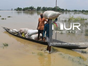 Villagers are shifting liquefied sacks of rice to a safer place in Nagaon District of Assam, India, on July 7, 2024. (