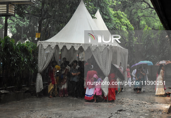 People are taking shelter during a heavy rain in Kolkata, India, on July 7, 2024. 