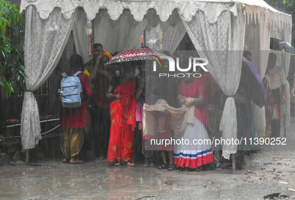 People are taking shelter during a heavy rain in Kolkata, India, on July 7, 2024. 