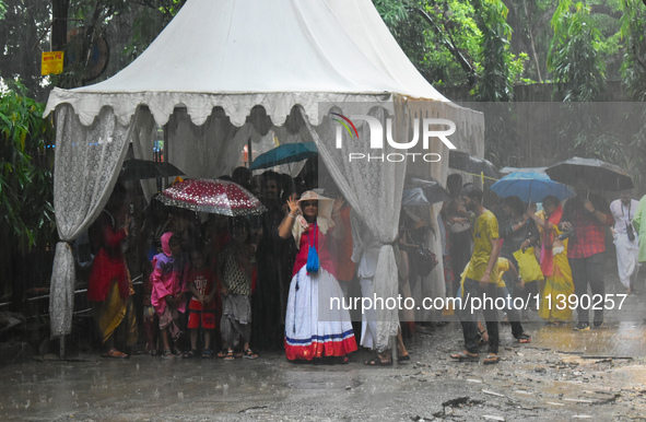 People are standing under a tent during heavy rain in Kolkata, India, on July 7, 2024. 