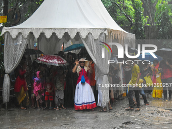 People are standing under a tent during heavy rain in Kolkata, India, on July 7, 2024. (