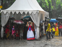 People are standing under a tent during heavy rain in Kolkata, India, on July 7, 2024. (