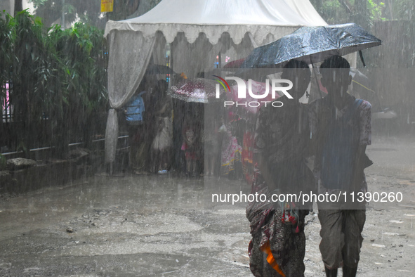 People are walking during heavy rain in Kolkata, India, on July 7, 2024. 