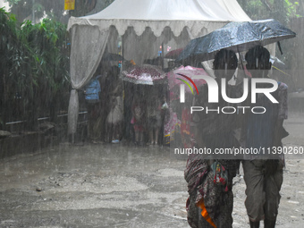 People are walking during heavy rain in Kolkata, India, on July 7, 2024. (