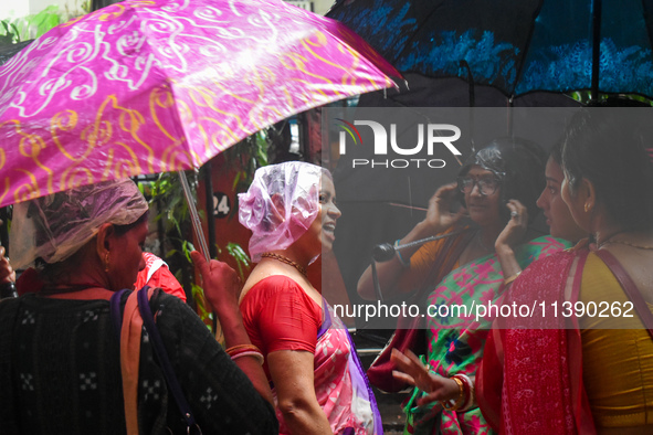 Women are covering their heads with plastic bags during heavy rain in Kolkata, India, on July 7, 2024. 