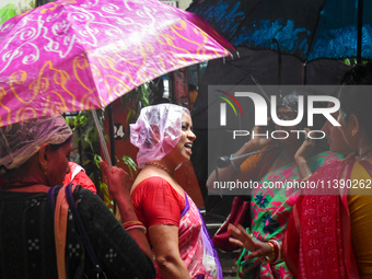 Women are covering their heads with plastic bags during heavy rain in Kolkata, India, on July 7, 2024. (