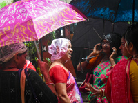 Women are covering their heads with plastic bags during heavy rain in Kolkata, India, on July 7, 2024. (