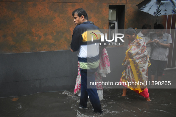 People are walking on the waterlogged street due to heavy rain in Kolkata, India, on July 7, 2024. 