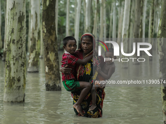 A woman is paddling through flooded water while carrying her children in Kurigram, Bangladesh, on July 7, 2024. (