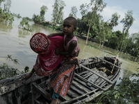 A woman is migrating locally with her daughter to high land as their home is submerged by flood water in Kurigram, Bangladesh, on July 7, 20...