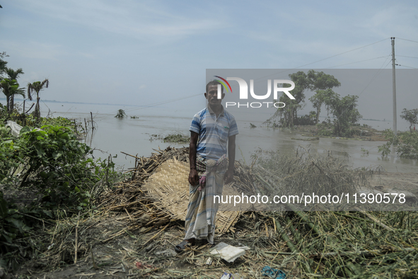 Nur Mohammad is standing in front of his damaged house by flood water in Kurigram, Bangladesh, on July 7, 2024. 