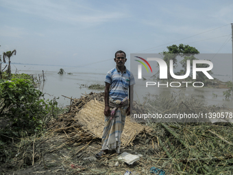 Nur Mohammad is standing in front of his damaged house by flood water in Kurigram, Bangladesh, on July 7, 2024. (