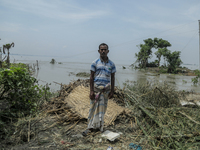 Nur Mohammad is standing in front of his damaged house by flood water in Kurigram, Bangladesh, on July 7, 2024. (