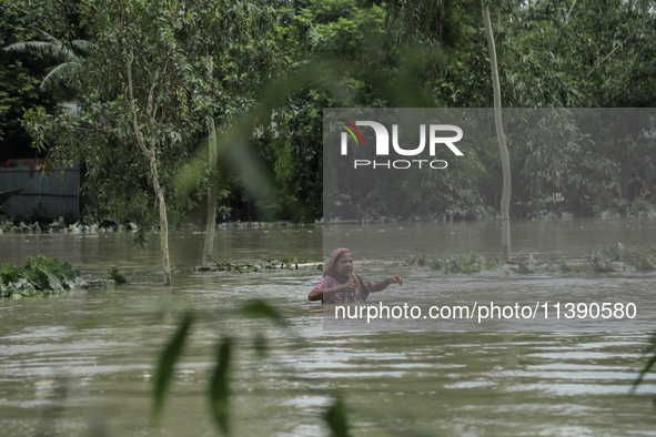 A woman is walking through chest-height flood water in Kurigram, Bangladesh, on July, 2024. 