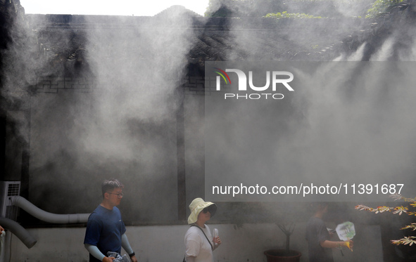 Visitors are playing in a lingering garden installed with spray in Suzhou, Jiangsu province, China, on July 8, 2024. In the hot summer, the...