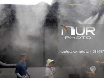 Visitors are playing in a lingering garden installed with spray in Suzhou, Jiangsu province, China, on July 8, 2024. In the hot summer, the...