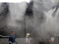 Visitors are playing in a lingering garden installed with spray in Suzhou, Jiangsu province, China, on July 8, 2024. In the hot summer, the...