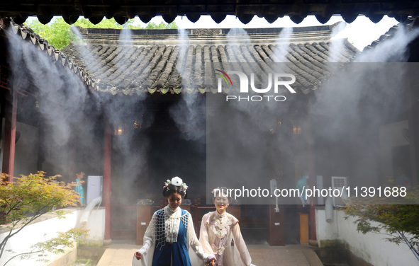 Visitors are playing in a lingering garden installed with spray in Suzhou, Jiangsu province, China, on July 8, 2024. In the hot summer, the...