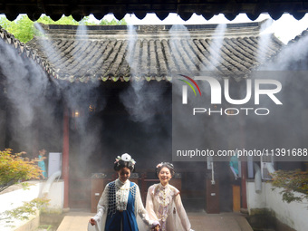 Visitors are playing in a lingering garden installed with spray in Suzhou, Jiangsu province, China, on July 8, 2024. In the hot summer, the...