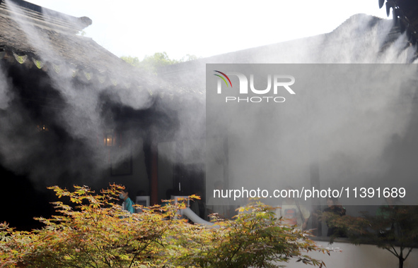 Visitors are playing in a lingering garden installed with spray in Suzhou, Jiangsu province, China, on July 8, 2024. In the hot summer, the...