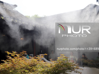 Visitors are playing in a lingering garden installed with spray in Suzhou, Jiangsu province, China, on July 8, 2024. In the hot summer, the...