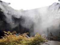 Visitors are playing in a lingering garden installed with spray in Suzhou, Jiangsu province, China, on July 8, 2024. In the hot summer, the...