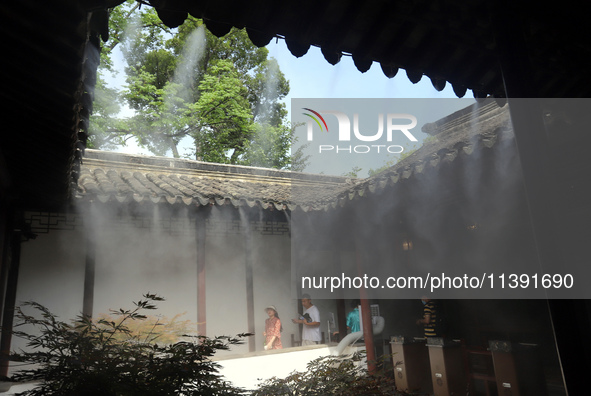 Visitors are playing in a lingering garden installed with spray in Suzhou, Jiangsu province, China, on July 8, 2024. In the hot summer, the...