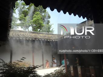 Visitors are playing in a lingering garden installed with spray in Suzhou, Jiangsu province, China, on July 8, 2024. In the hot summer, the...