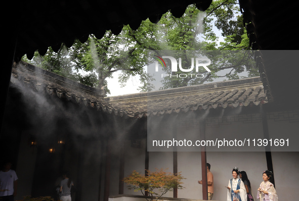 Visitors are playing in a lingering garden installed with spray in Suzhou, Jiangsu province, China, on July 8, 2024. In the hot summer, the...