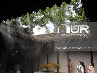 Visitors are playing in a lingering garden installed with spray in Suzhou, Jiangsu province, China, on July 8, 2024. In the hot summer, the...