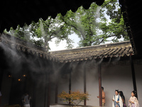 Visitors are playing in a lingering garden installed with spray in Suzhou, Jiangsu province, China, on July 8, 2024. In the hot summer, the...