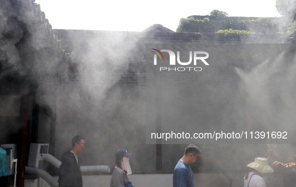 Visitors are playing in a lingering garden installed with spray in Suzhou, Jiangsu province, China, on July 8, 2024. In the hot summer, the...