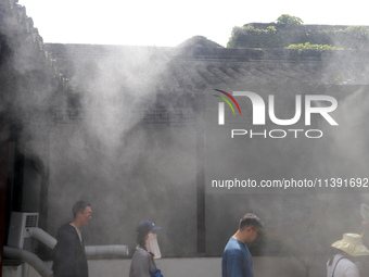 Visitors are playing in a lingering garden installed with spray in Suzhou, Jiangsu province, China, on July 8, 2024. In the hot summer, the...