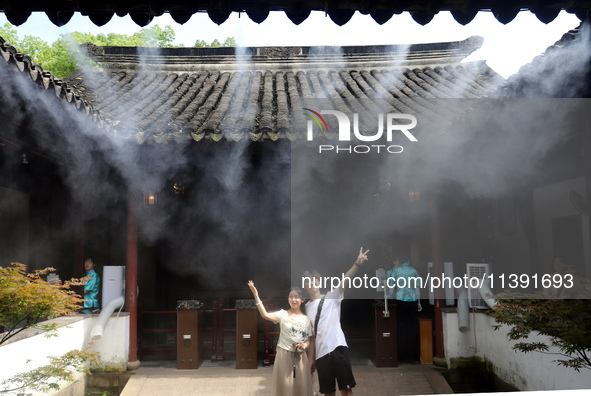 Visitors are playing in a lingering garden installed with spray in Suzhou, Jiangsu province, China, on July 8, 2024. In the hot summer, the...