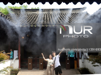 Visitors are playing in a lingering garden installed with spray in Suzhou, Jiangsu province, China, on July 8, 2024. In the hot summer, the...