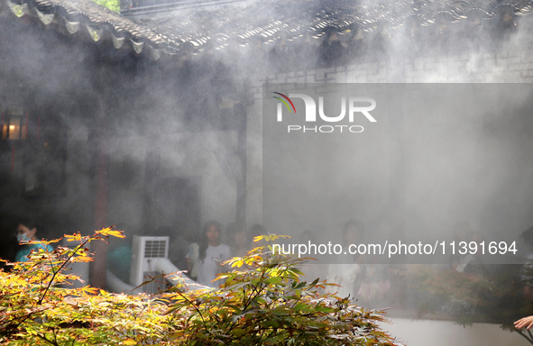 Visitors are playing in a lingering garden installed with spray in Suzhou, Jiangsu province, China, on July 8, 2024. In the hot summer, the...