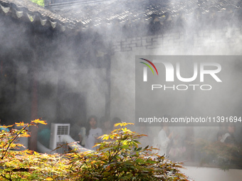 Visitors are playing in a lingering garden installed with spray in Suzhou, Jiangsu province, China, on July 8, 2024. In the hot summer, the...