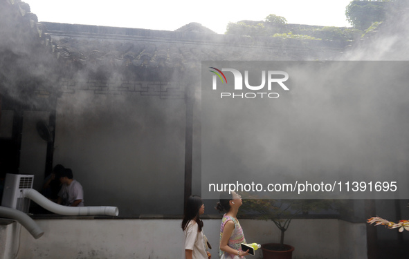 Visitors are playing in a lingering garden installed with spray in Suzhou, Jiangsu province, China, on July 8, 2024. In the hot summer, the...