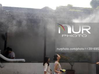 Visitors are playing in a lingering garden installed with spray in Suzhou, Jiangsu province, China, on July 8, 2024. In the hot summer, the...