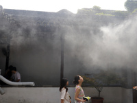 Visitors are playing in a lingering garden installed with spray in Suzhou, Jiangsu province, China, on July 8, 2024. In the hot summer, the...