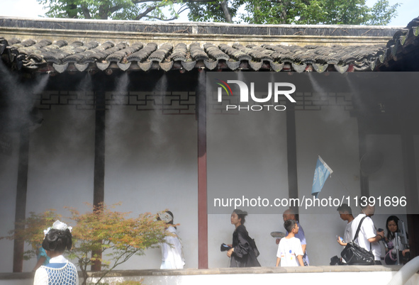 Visitors are playing in a lingering garden installed with spray in Suzhou, Jiangsu province, China, on July 8, 2024. In the hot summer, the...