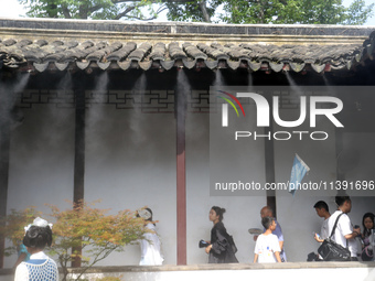 Visitors are playing in a lingering garden installed with spray in Suzhou, Jiangsu province, China, on July 8, 2024. In the hot summer, the...