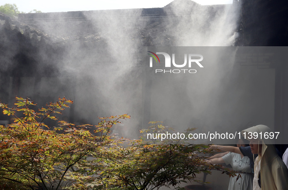 Visitors are playing in a lingering garden installed with spray in Suzhou, Jiangsu province, China, on July 8, 2024. In the hot summer, the...