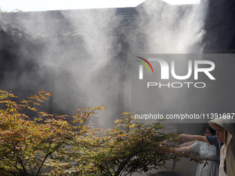 Visitors are playing in a lingering garden installed with spray in Suzhou, Jiangsu province, China, on July 8, 2024. In the hot summer, the...