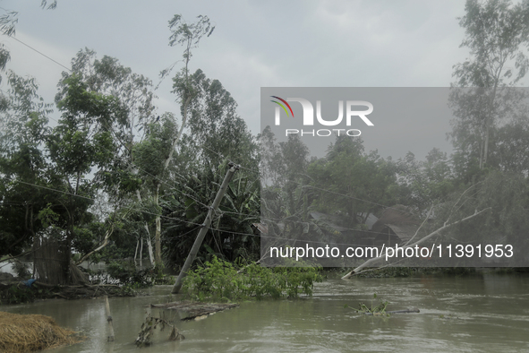 A wiped-off electricity pole is being caused by a heavy flood water wave in Kurigram, Bangladesh, on July 8, 2024. 