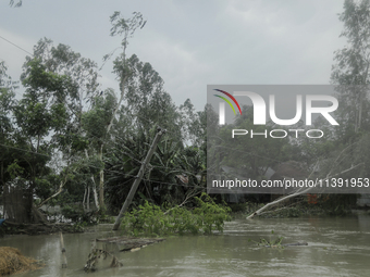 A wiped-off electricity pole is being caused by a heavy flood water wave in Kurigram, Bangladesh, on July 8, 2024. (