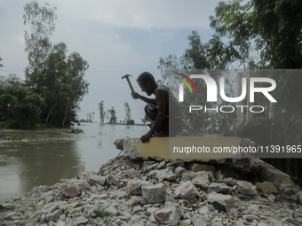 A man is demolishing the remaining structure of his house, washed off by flood water in Kurigram, Bangladesh, on July 8, 2024. (