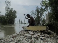 A man is demolishing the remaining structure of his house, washed off by flood water in Kurigram, Bangladesh, on July 8, 2024. (