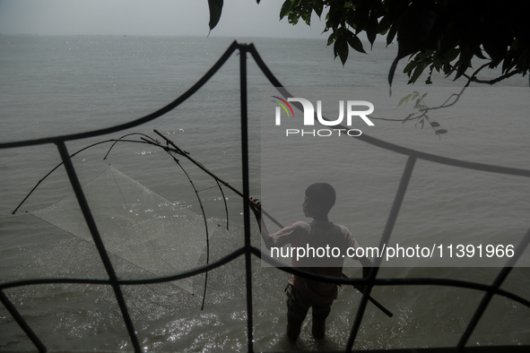 A boy is trying to catch fish from his washed-off house due to flood water in Kurigram, Bangladesh, on July 8, 2024. 